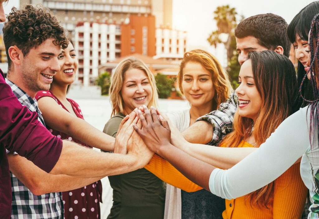 Young happy people stacking hands outdoor - Focus on hands
